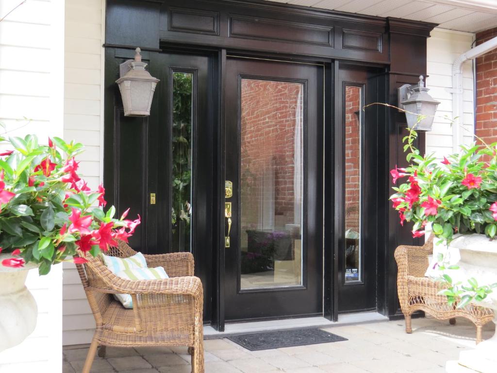 una puerta negra con flores y sillas de mimbre en Stone Garden Inn, en Trenton
