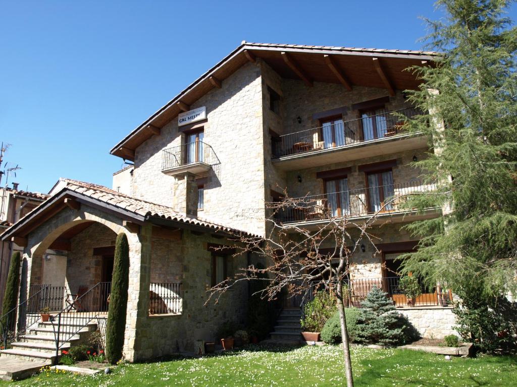 een groot stenen huis met een trap en een tuin bij Hostal Cal Mestre in Vilallonga de Ter