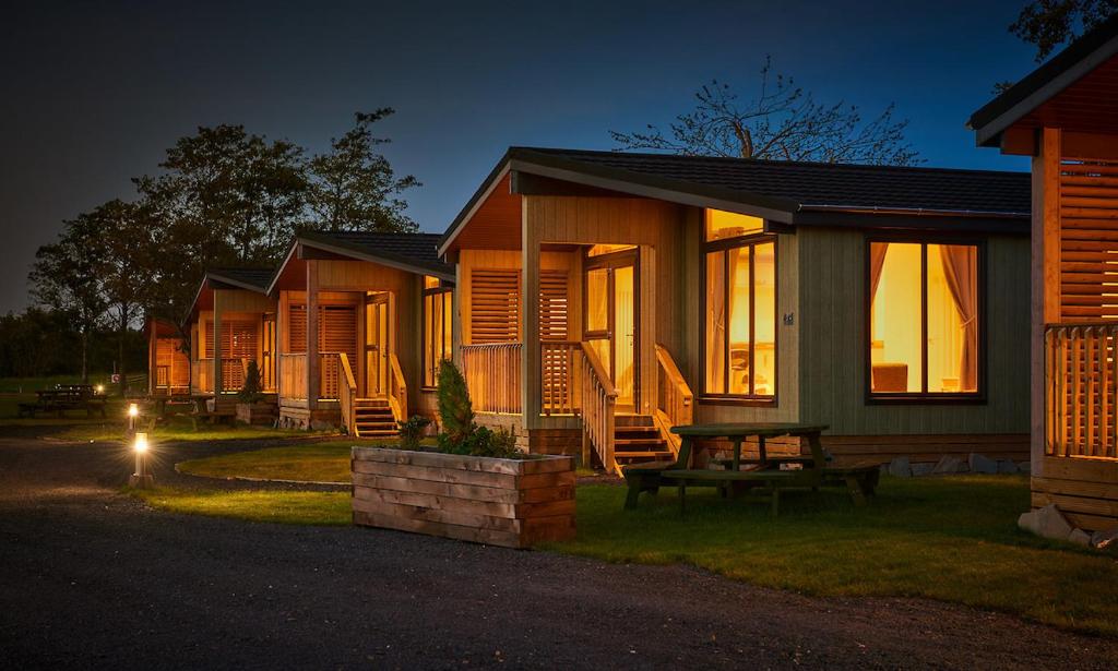 uma fila de chalés à noite com uma mesa de piquenique em Silverwood Luxury Lodges & Bistro Barn em Perth