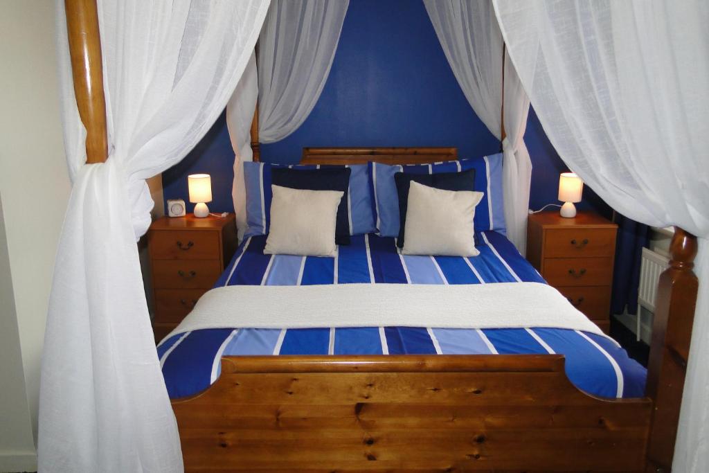1 dormitorio azul con 1 cama con cortinas azules y blancas en Windsor Hotel, en Blackpool