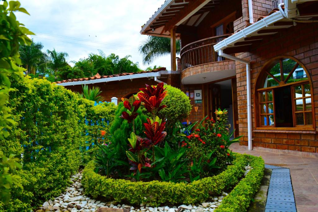 einen Garten vor einem Haus mit Blumen in der Unterkunft Hostal San Jorge in Pereira