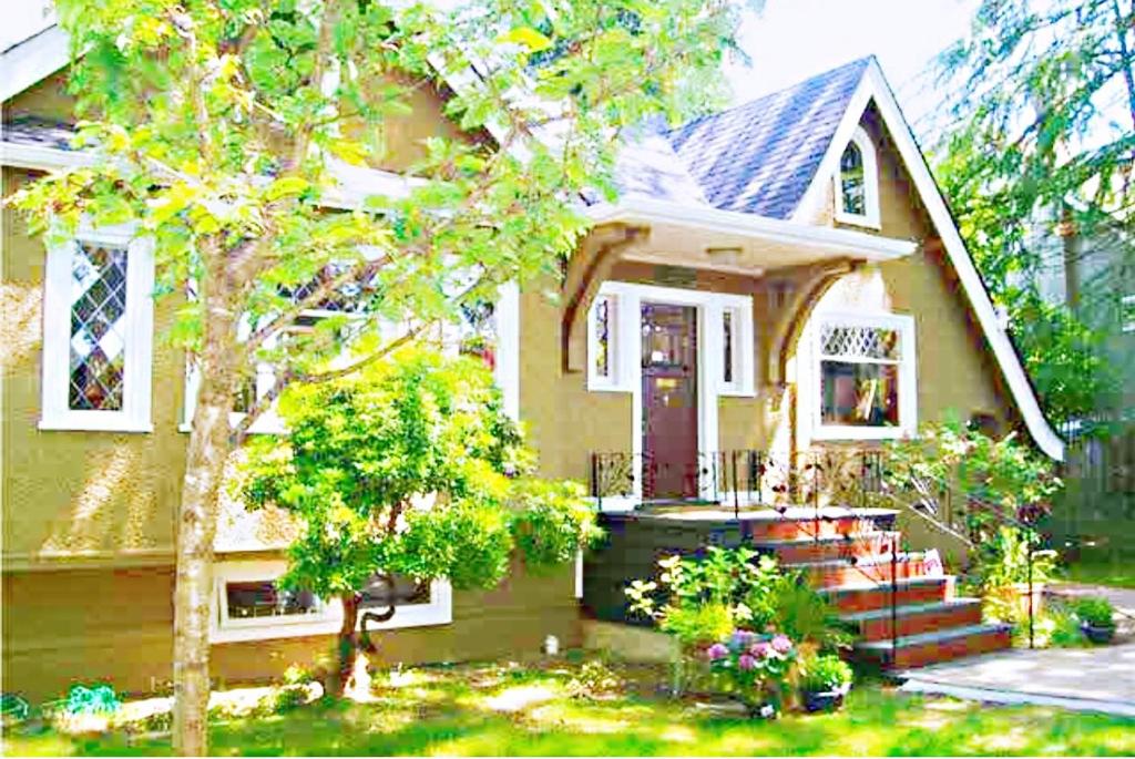 溫哥華的住宿－鄧巴之家民宿，一间黄色的小房子,设有红色的门和楼梯