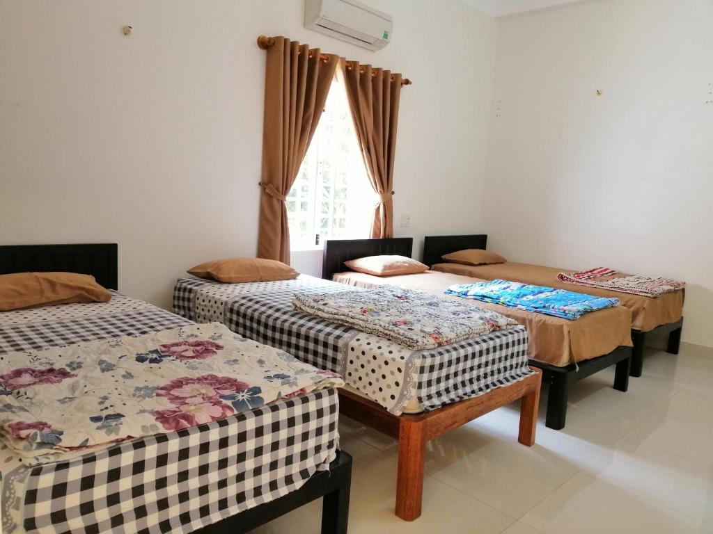 a room with three beds and a window at Skybird Homestay in Hoi An