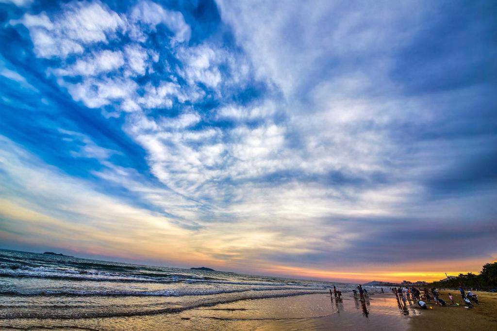 a group of people on the beach at sunset at Ocean Sonic Resort Sanya in Sanya