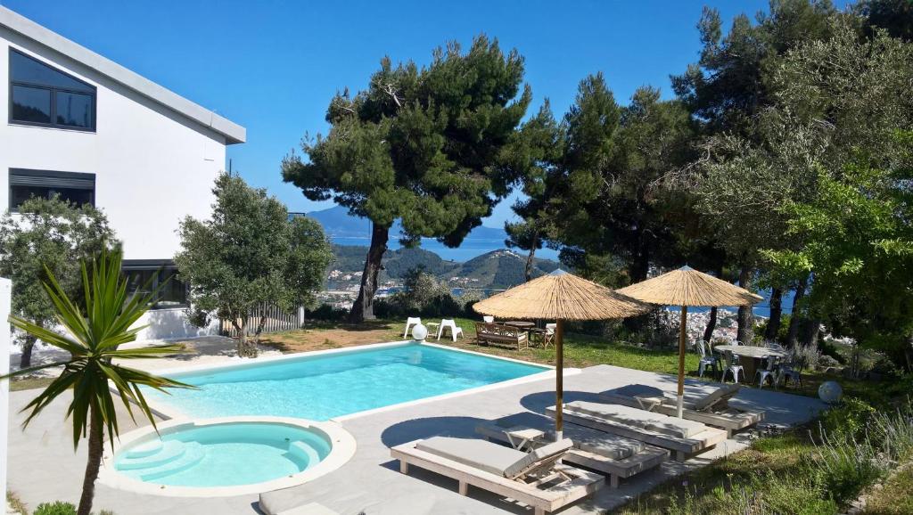 a swimming pool with chairs and umbrellas next to a house at Entechnos Living in Skiathos Town