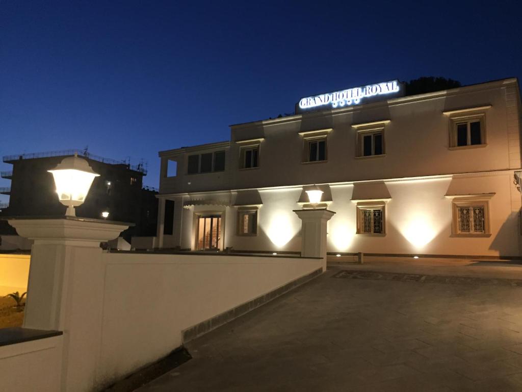 un bâtiment blanc avec un panneau sur lui la nuit dans l'établissement Grand Hotel Royal, à Pompéi