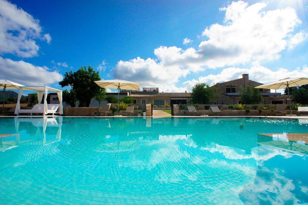 uma grande piscina com água azul e guarda-sóis em Ca Na Nina em Sant Llorenç des Cardassar