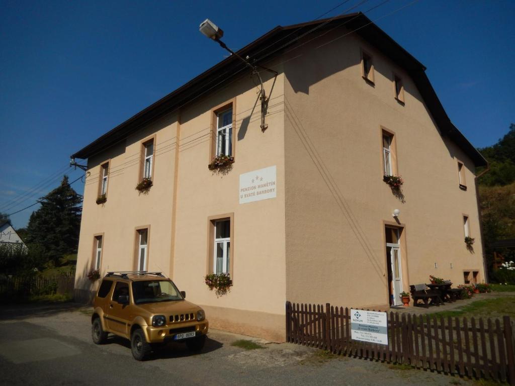 um jipe amarelo estacionado em frente a um edifício em PENZION MANĚTÍN u Sv. Barbory em Manětín