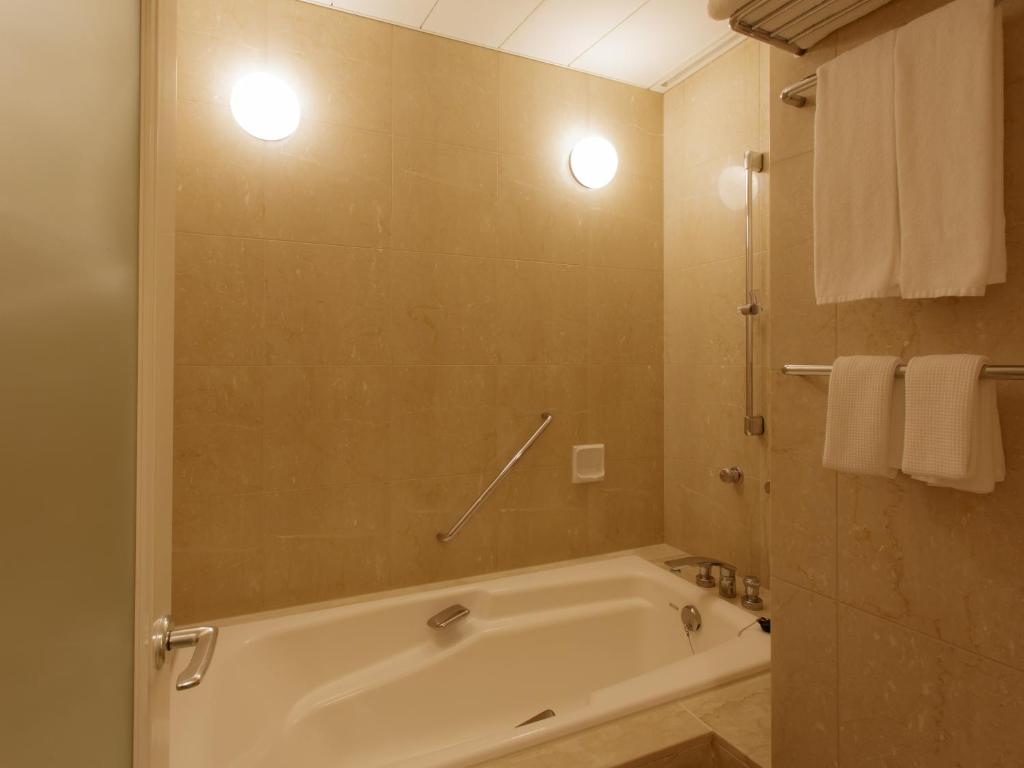 a bathroom with a tub and a shower with towels at Hotel Grand Arc Hanzomon in Tokyo