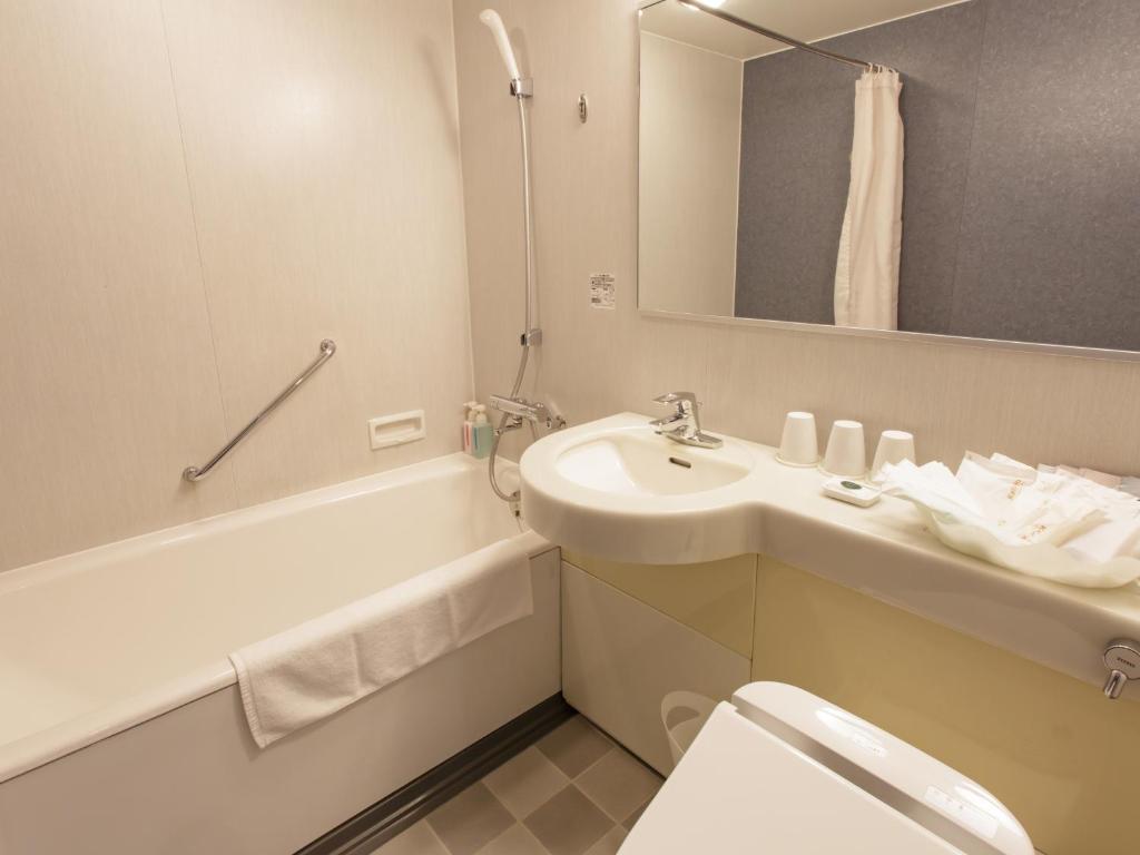 a bathroom with a sink and a toilet and a mirror at Hotel Grand Arc Hanzomon in Tokyo