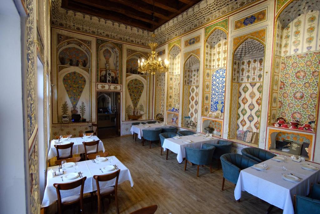 un comedor con mesas blancas y sillas azules en Lyabi House Hotel, en Bukhara