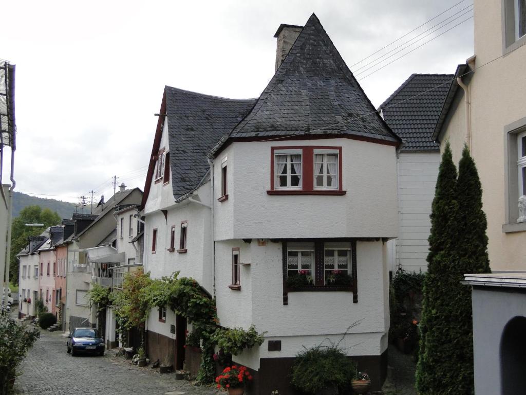 a white house with a black roof on a street at Altes Spitzhaus an der Goldroul in Senheim