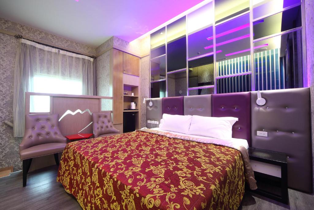 a bedroom with a large bed and two chairs at Rose Garden Motel in Qishan