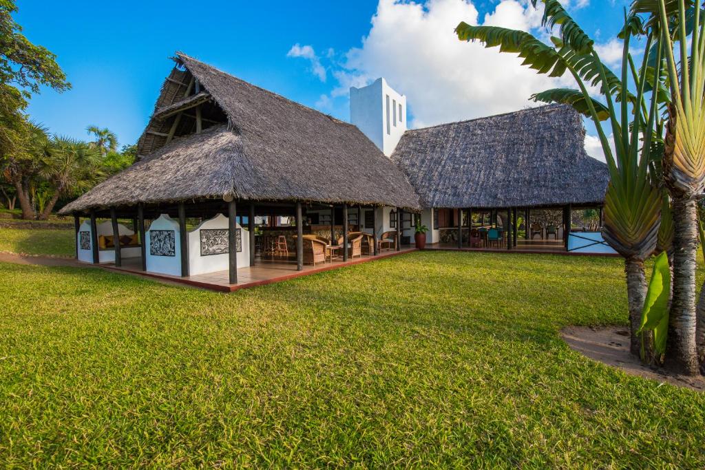 a building with a thatched roof on a grass field at Amani Beach Resort in Kutani