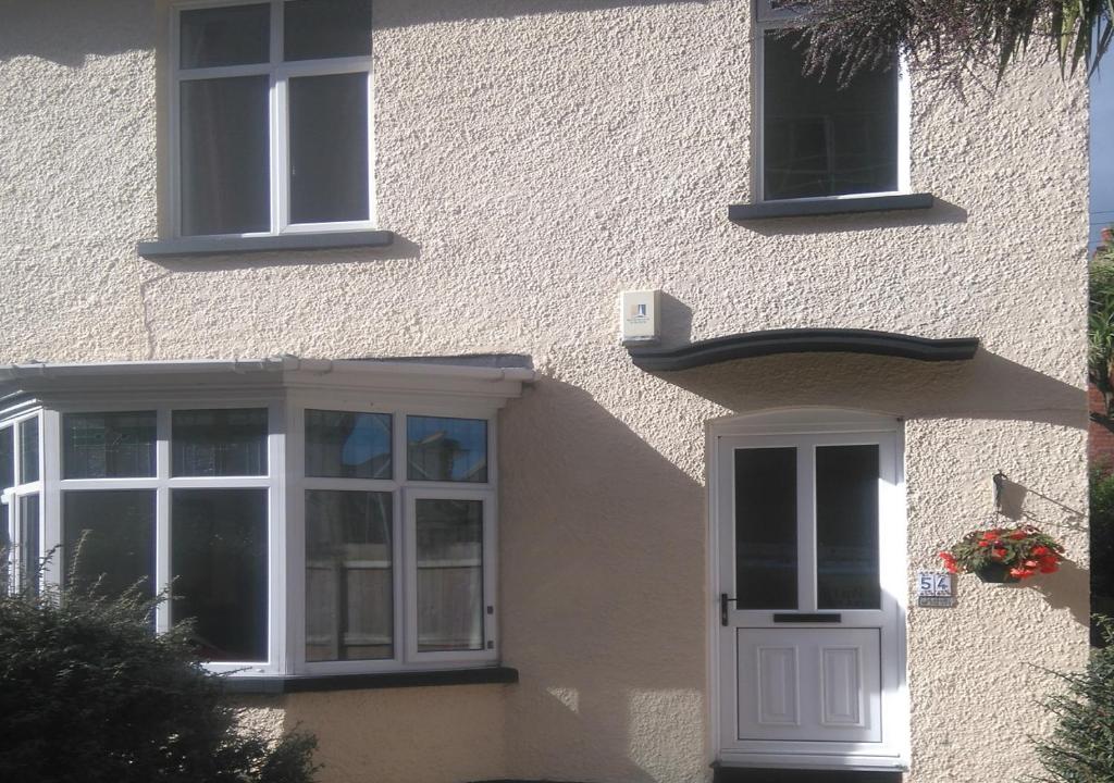 um edifício com uma porta branca e janelas em Simon's Cosy House em Bangor