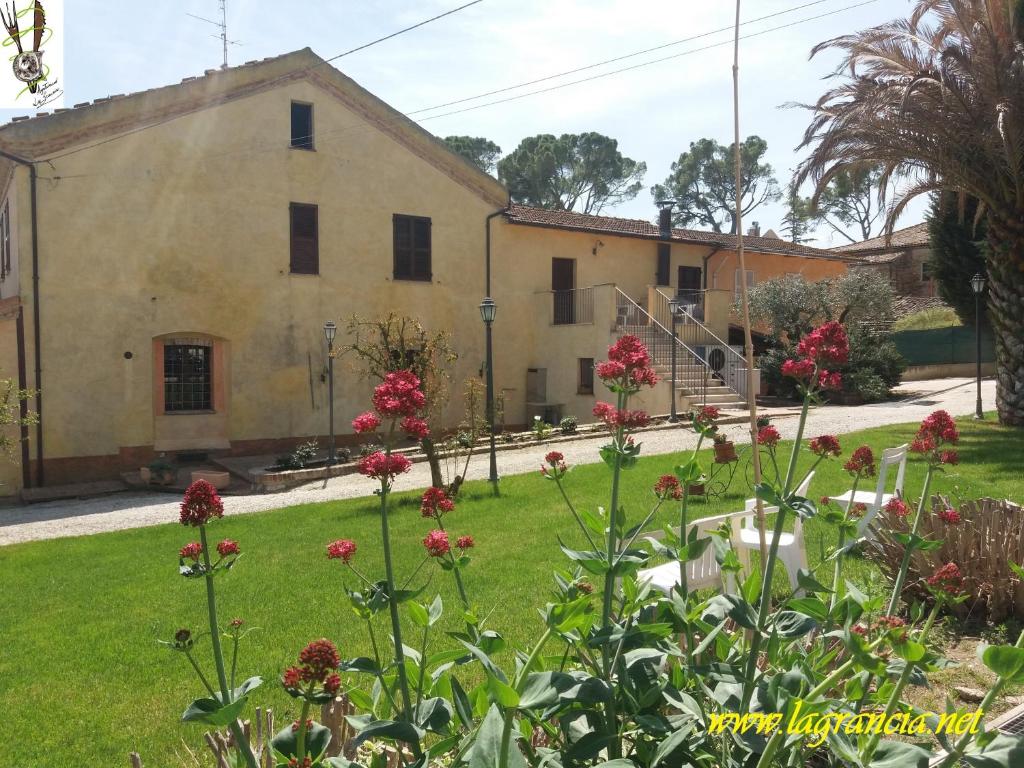 um edifício antigo com flores em frente em "La Grancia" Country House em Treia