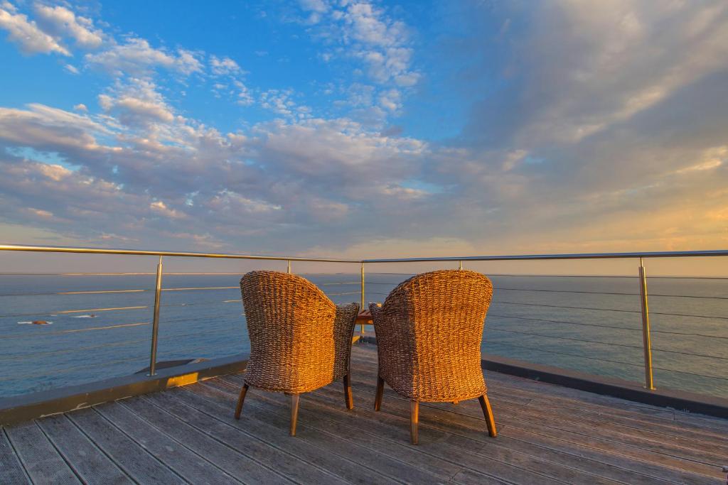 dos sillas sentadas en una terraza con vistas al océano en Alexander Guest House, en Knysna