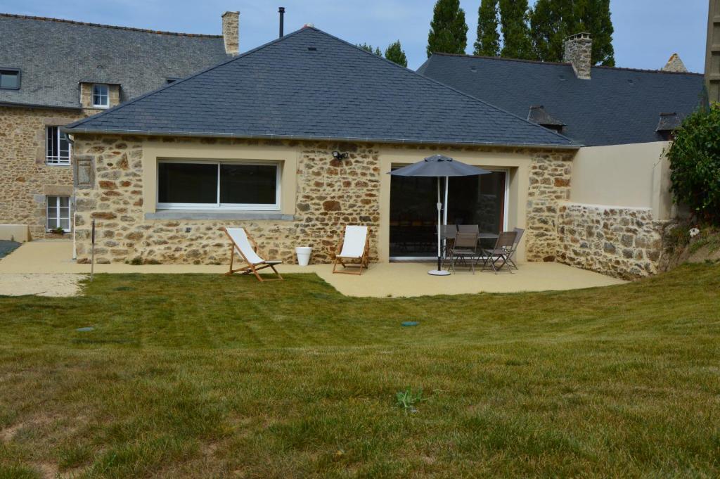 een stenen huis met 2 stoelen en een parasol bij Gîte le Grand Bé in Saint-Malo