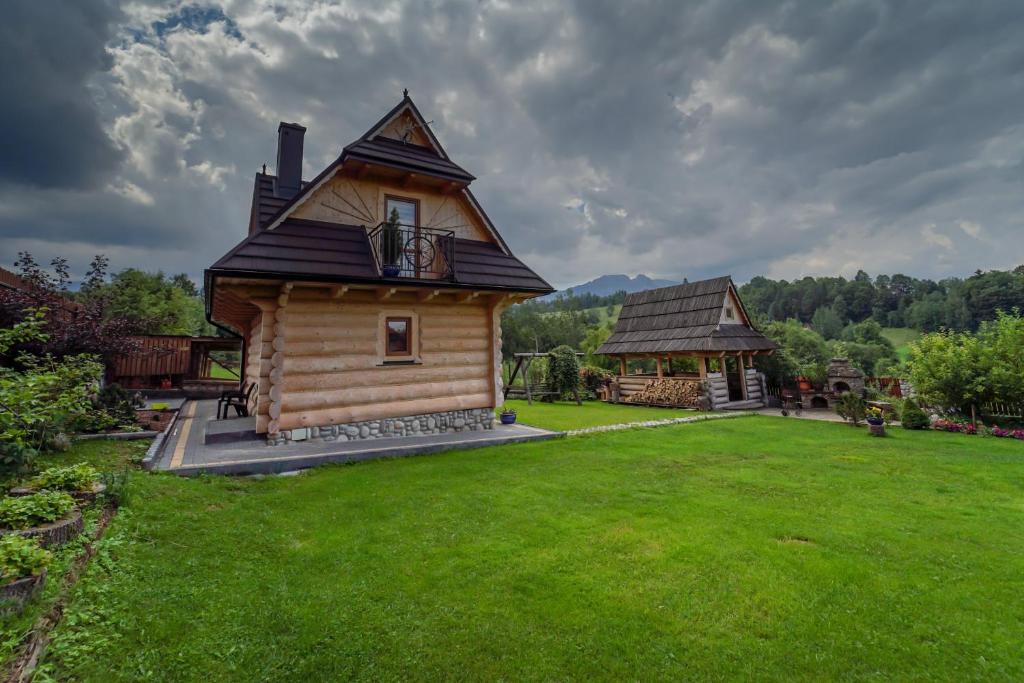 a log cabin in a field of green grass at Domek Regionalny Dan Pio in Zakopane