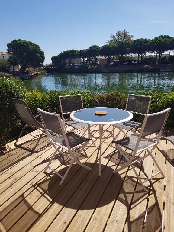 une table et quatre chaises sur une terrasse avec une rivière dans l'établissement Marina village, à Saint Cyprien Plage