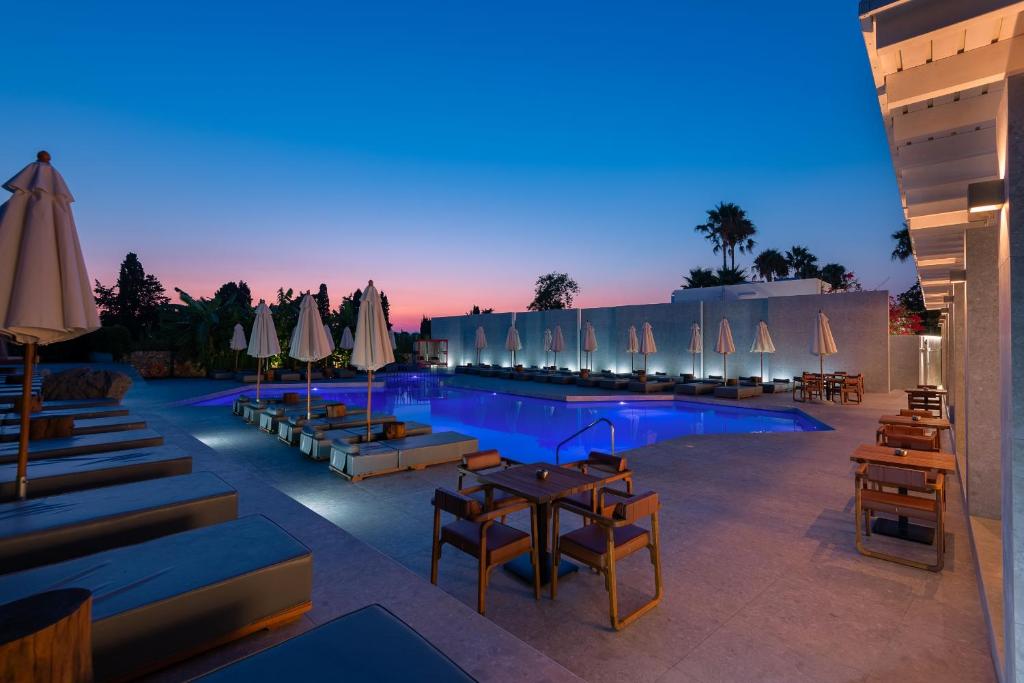 a swimming pool with tables and umbrellas and chairs at Diamond Boutique Hotel in Kos