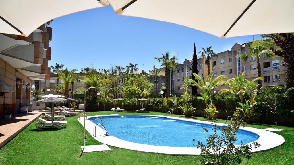 a swimming pool in the middle of a yard with umbrellas at Hotel TRH La Motilla in Dos Hermanas