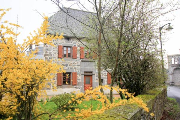a stone house with red windows and a stone wall at Le Cottage Lavastrie in Lavastrie