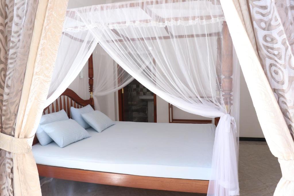 un letto a baldacchino con tende bianche di Villa Sureka a Hikkaduwa