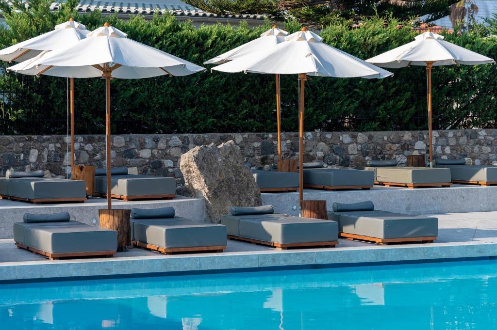 a group of lounge chairs and umbrellas next to a swimming pool at Diamond Boutique Hotel in Kos
