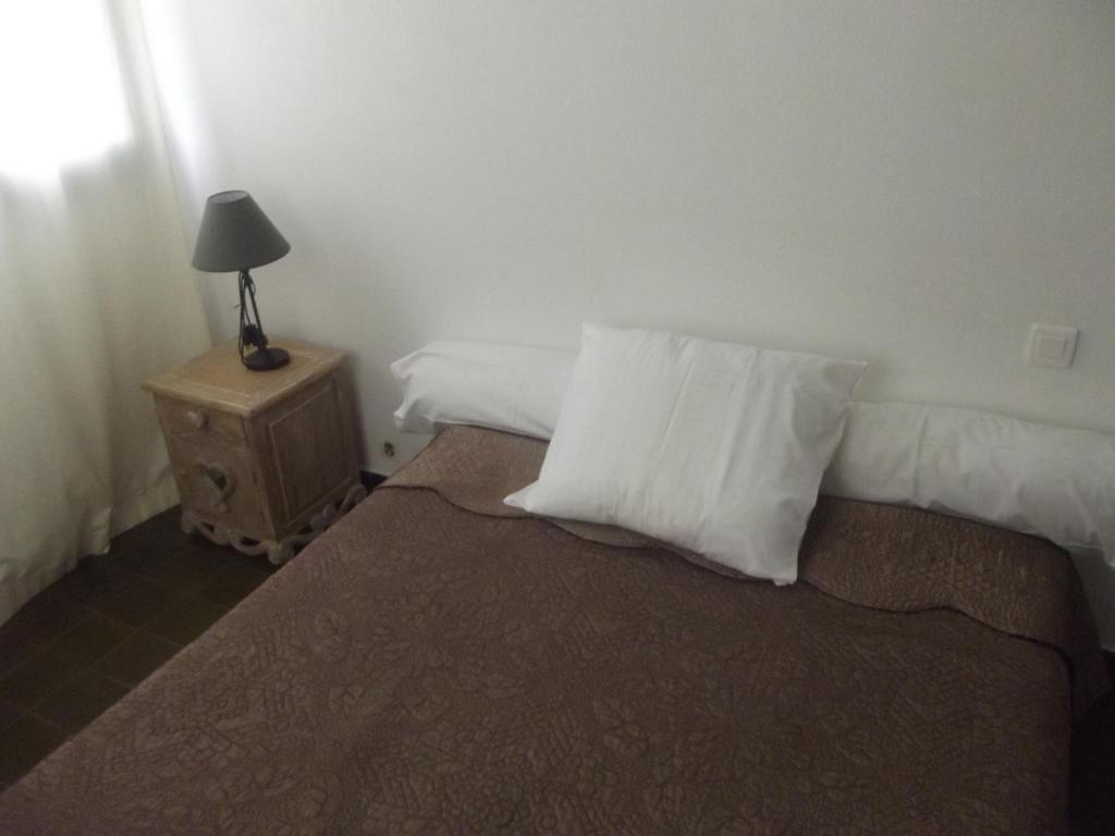 1 cama con 2 almohadas y mesita de noche con lámpara en Hotel U Liccedu, en Bustanico