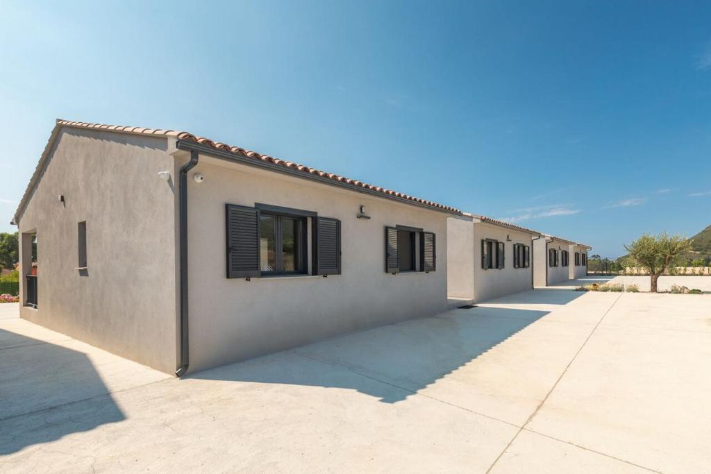 a white building with black shuttered windows on it at Le Domaine De Marie in Palasca