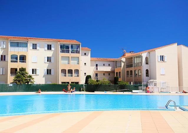 uma piscina em frente a alguns edifícios de apartamentos em le lagon bleu - Fréjus em Fréjus