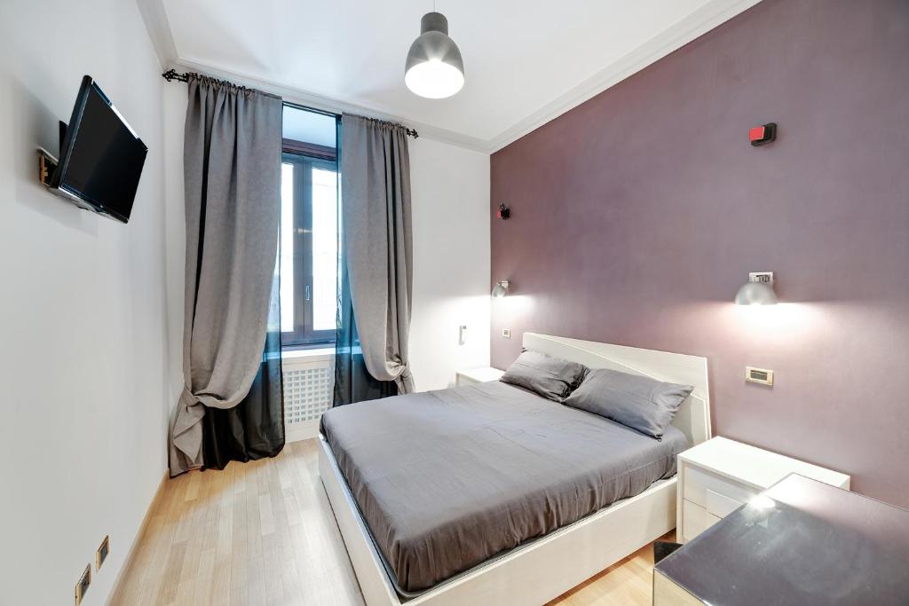 um pequeno quarto com uma cama e uma televisão em Peroni 8 Pax Brand New Apartment em Roma