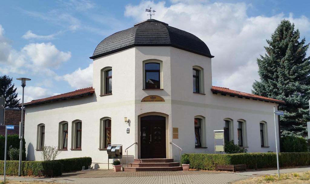 a white church with a black roof at Ferienwohnung "Burgblick" in Heldrungen