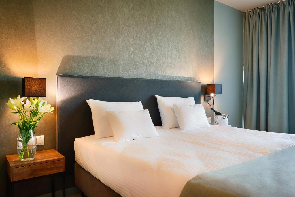 1 dormitorio con 1 cama grande con sábanas y almohadas blancas en Focus Hotel Poznań en Poznan