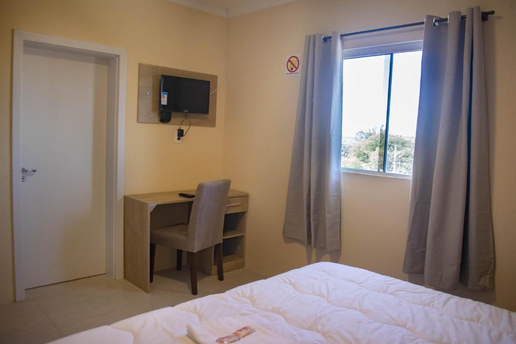 sypialnia z biurkiem, łóżkiem i oknem w obiekcie Hotel Marrocos w mieście Pelotas