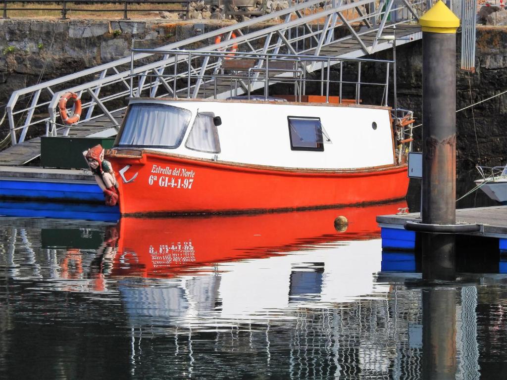 un barco rojo y blanco sentado en el agua en Estrella del Norte, en Villaviciosa