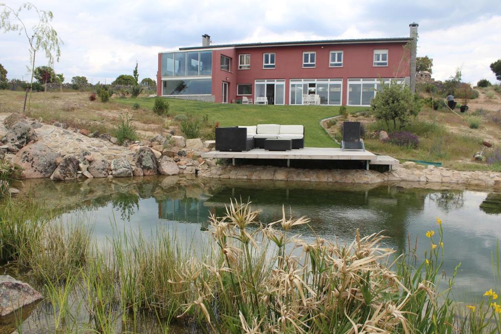 a house on a hill with a pond in front of it at Finca el enebro in Valdemorillo