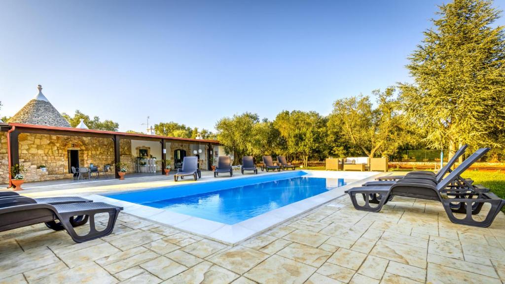 a swimming pool with lounge chairs next to a house at Trullo degli Augelli in San Michele Salentino