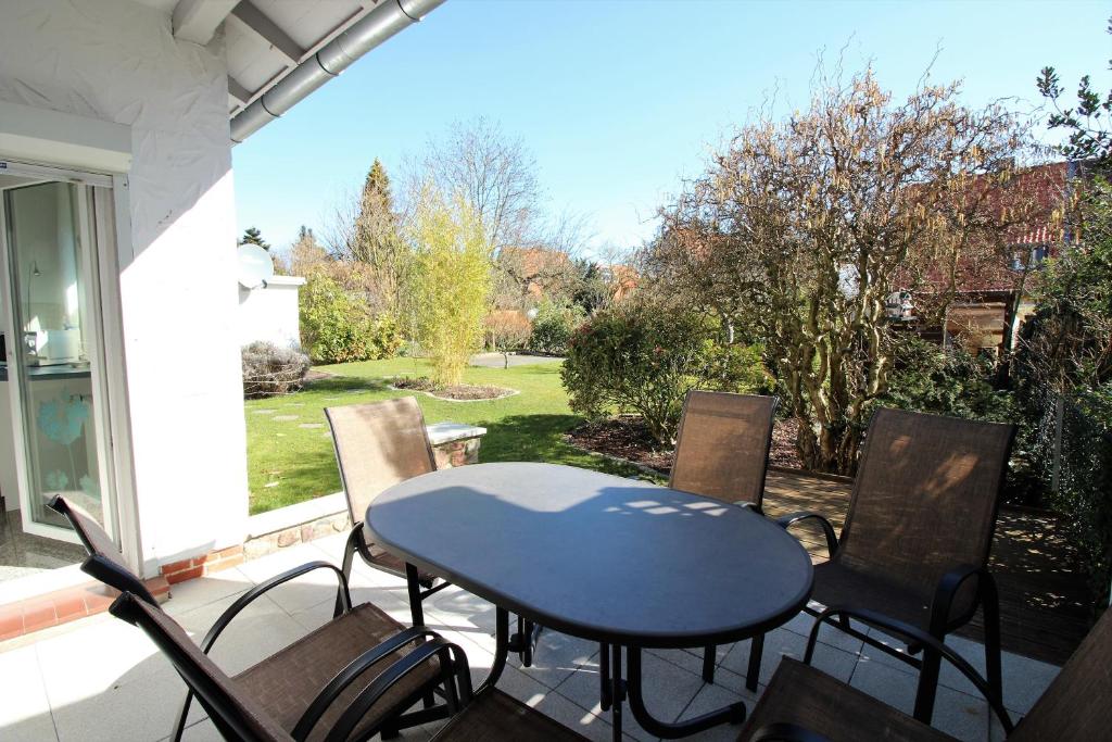 a table and chairs on a patio with a view of a yard at Am Apfelgarten-2 Apartments mit eigenem Parkplatz-Flörekeweg in Lüneburg