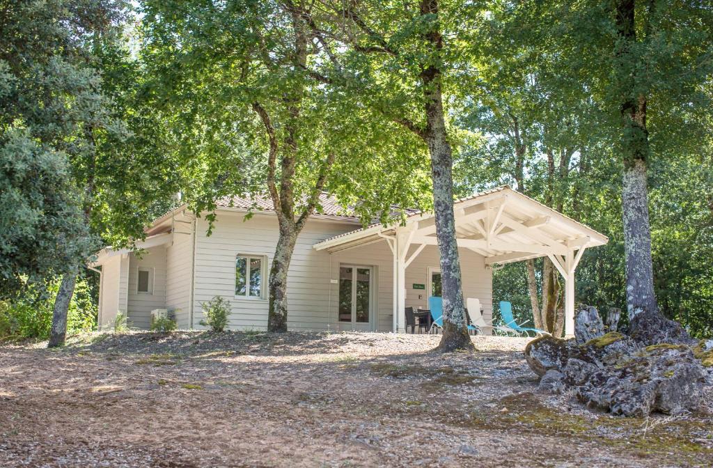 a white house with a porch and trees at Chalet BIRON - Piscine & Tennis - Gîtes de Poubille in Blanquefort-sur-Briolance