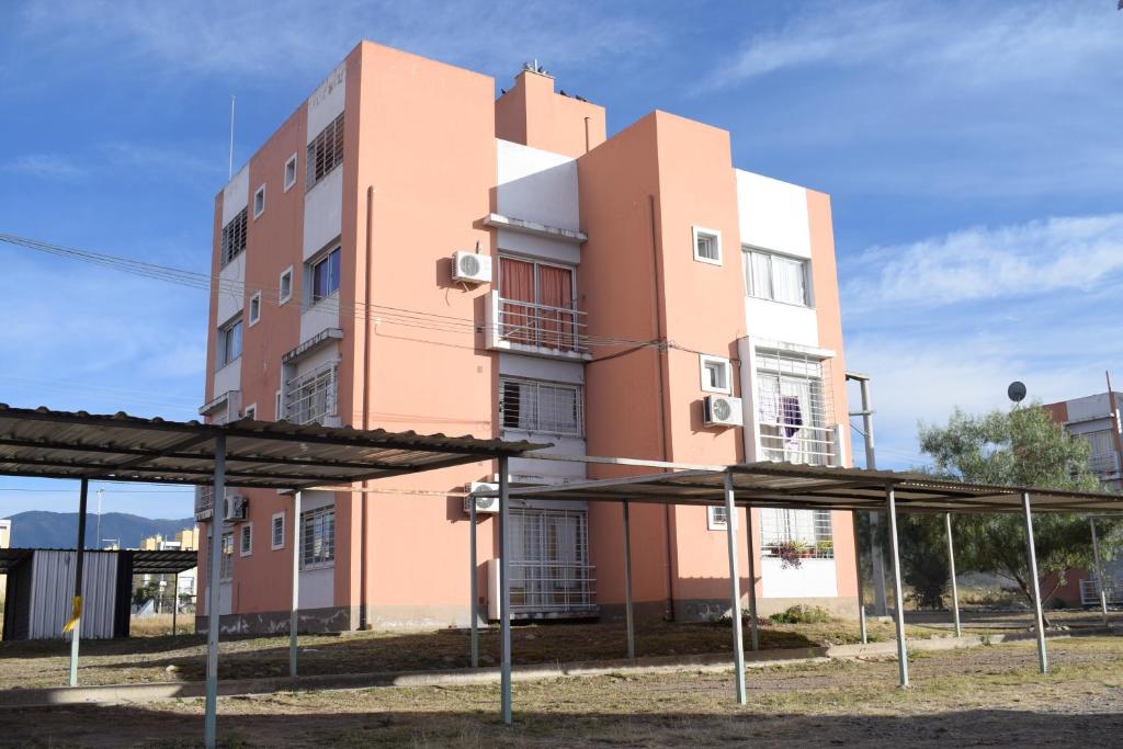 ein großes rosafarbenes Gebäude mit Sonnenschirmen davor in der Unterkunft Acogedor departamento cerca de rios, montañas y naturaleza in Salta