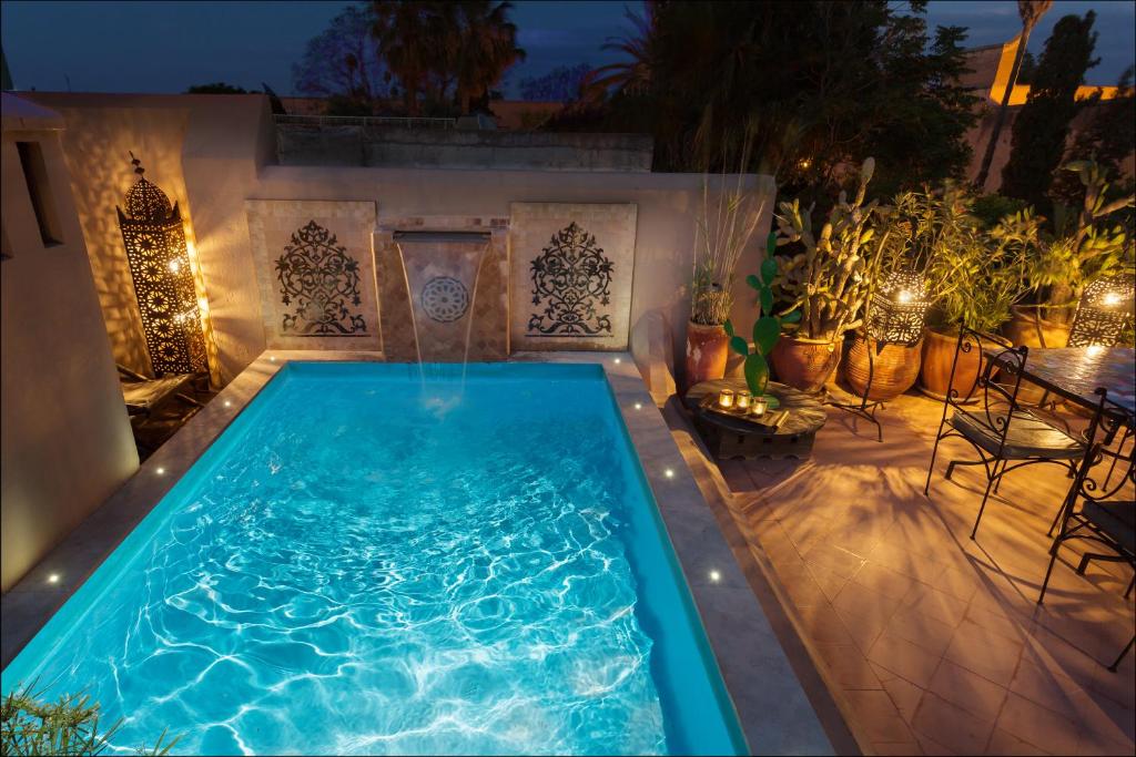 a swimming pool in a backyard at night at Riad Swaka in Marrakesh