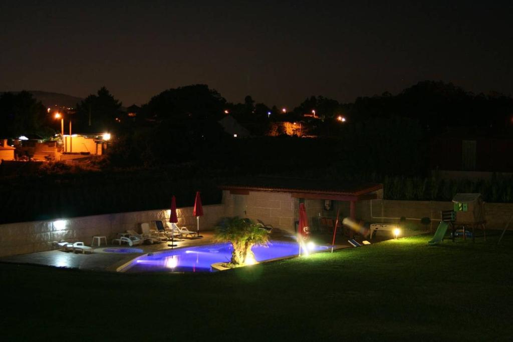 einen Hinterhof in der Nacht mit einem Pool mit Lichtern in der Unterkunft A Cacheira in Sanxenxo