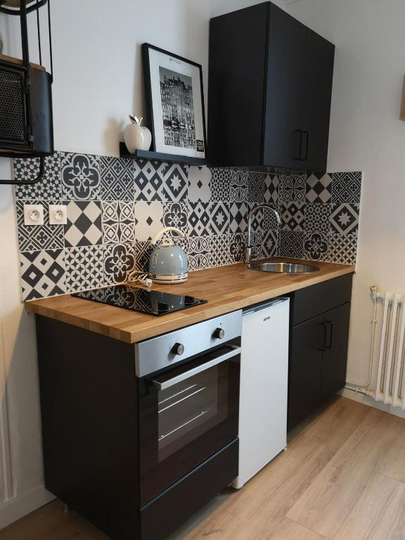 - une cuisine avec du carrelage noir et blanc sur le mur dans l'établissement Un Parfum D'embruns Hypercentre Honfleur, fibre, à Honfleur