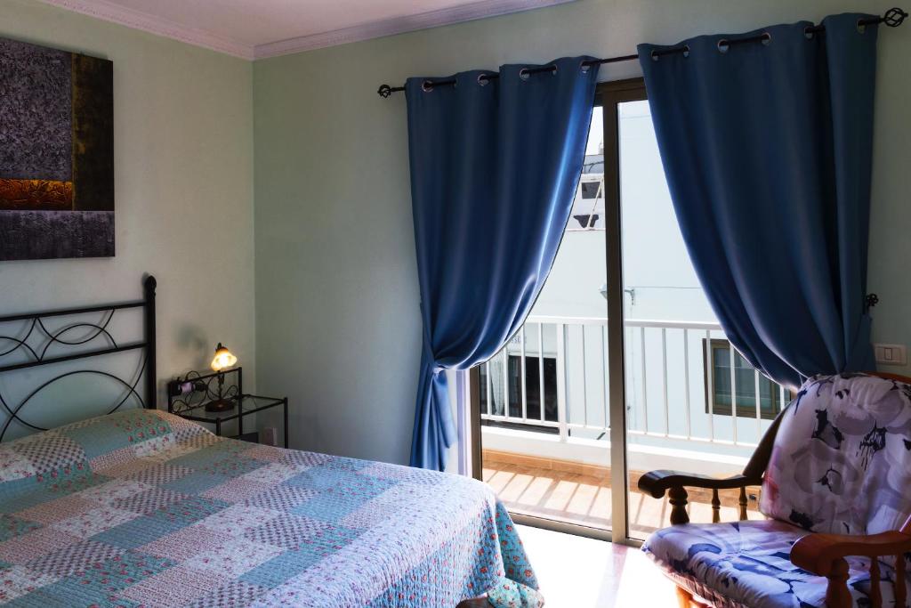 ラス・ガジェタスにあるTypical Canarian apartmentのベッドルーム(青いカーテン、ベッド1台、バルコニー付)