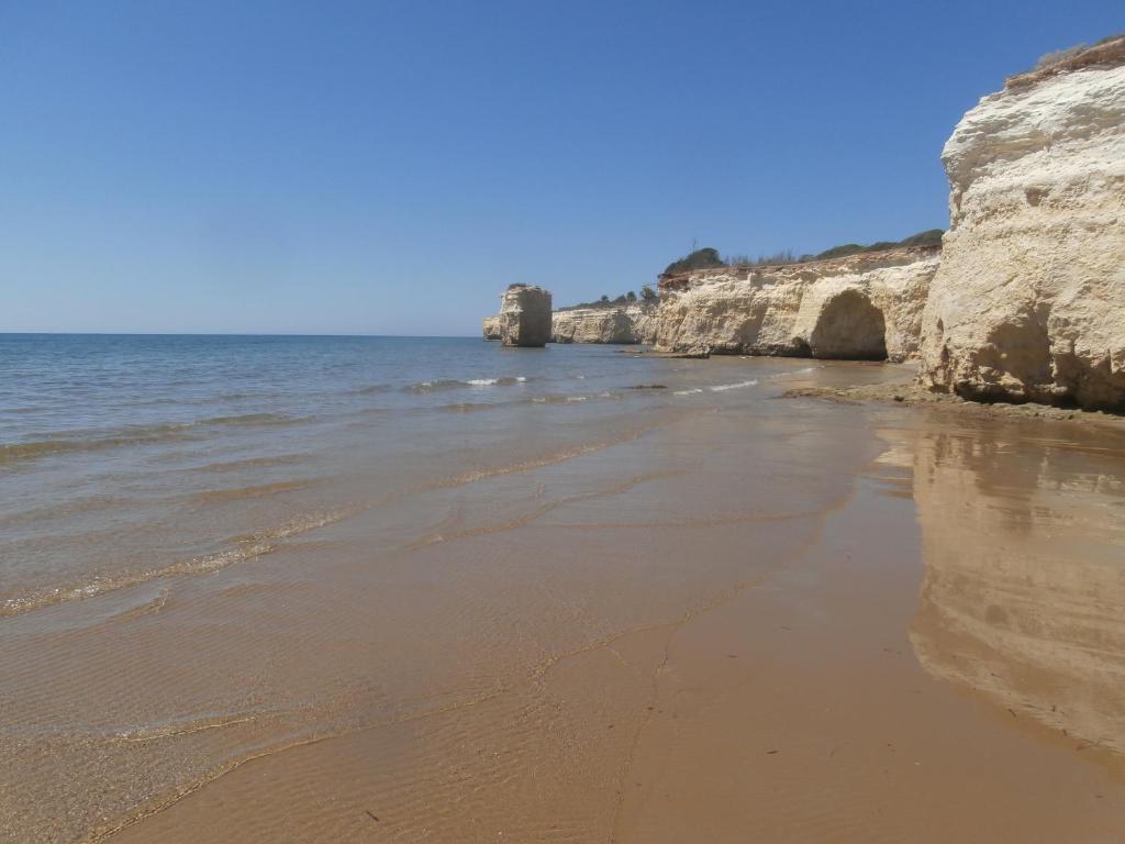 a sandy beach with rocks in the water at VILLA FIOR D'OLEANDRO in Santa Maria Del Focallo