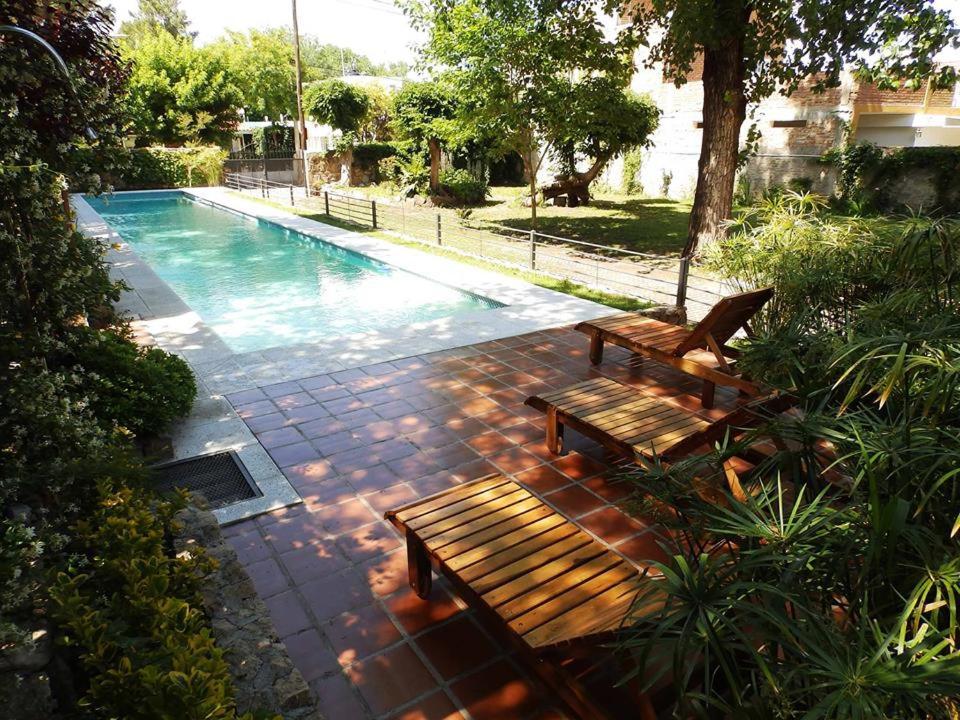 2 bancos de madera situados junto a una piscina en Hotel Sierras en Mina Clavero