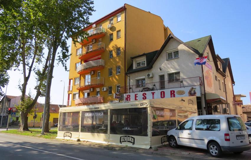 ein weißes Auto, das vor einem gelben Gebäude parkt in der Unterkunft Domin Osijek in Osijek