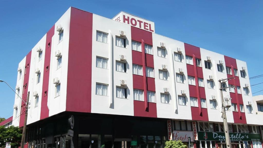 a red and white hotel on a city street at Hotel Ricardi Express in Cascavel